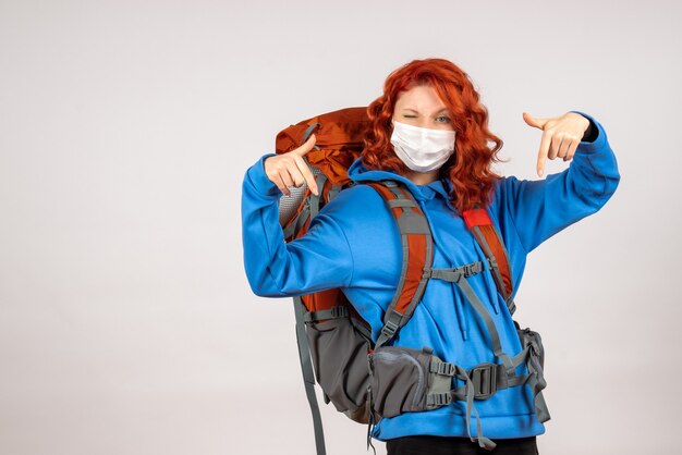 Turista femminile di vista frontale che va in viaggio in montagna in maschera con lo zaino