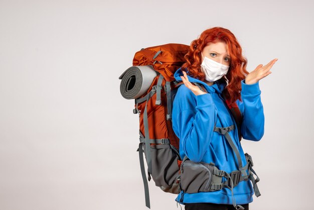 Turista femminile di vista frontale che va in viaggio in montagna in maschera con lo zaino