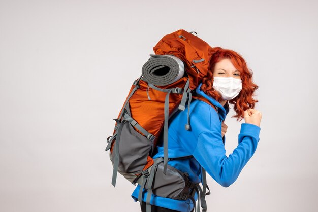 Turista femminile di vista frontale che va in viaggio in montagna in maschera con lo zaino