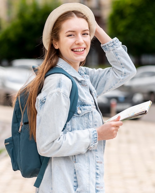 Turista femminile lateralmente che tiene il suo cappello