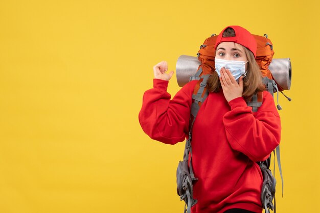 Turista femminile perplesso vista frontale con lo zaino e la maschera che indica dietro