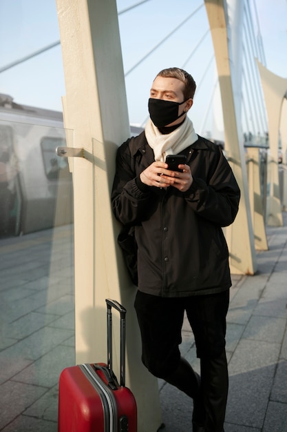 Turista maschio con bagagli e smartphone