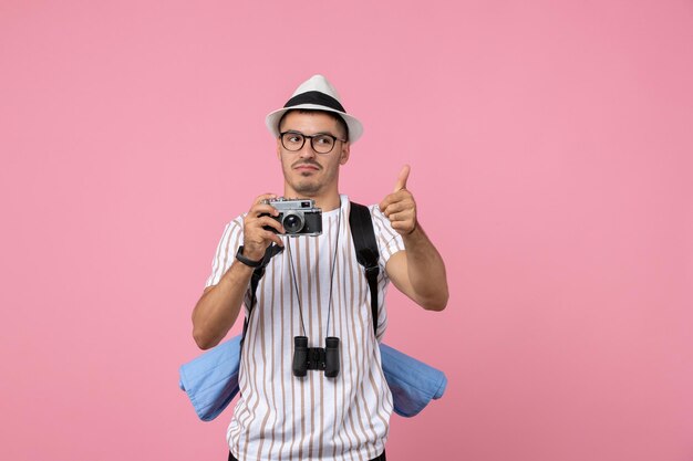 Turista maschio di vista frontale con la macchina fotografica sul turista rosa di colore di emozione della parete