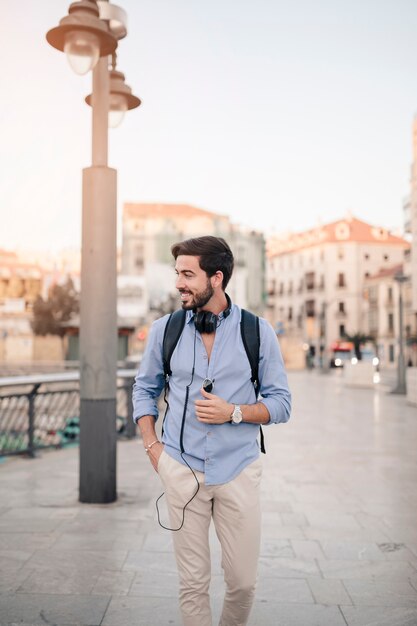 Turista maschio sorridente che cammina sulla pavimentazione