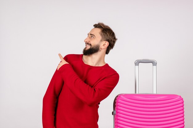 Turista maschio vista frontale con borsa rosa sul muro bianco