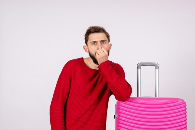 Turista maschio vista frontale con borsa rosa sul muro bianco