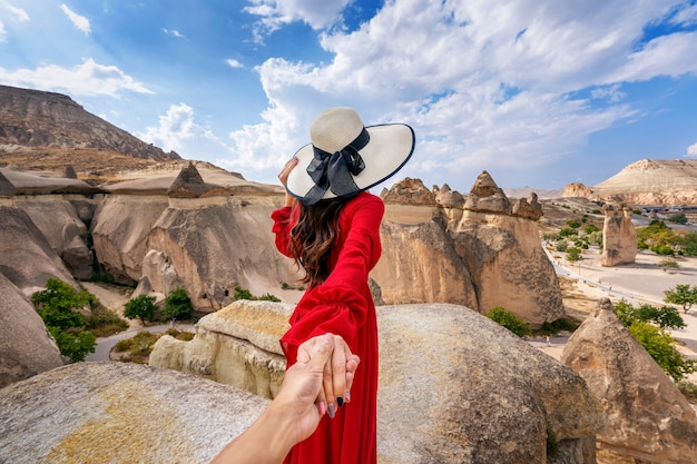 Turiste che tengono la mano dell'uomo e lo conducono ai camini delle fate in Cappadocia, Turchia.