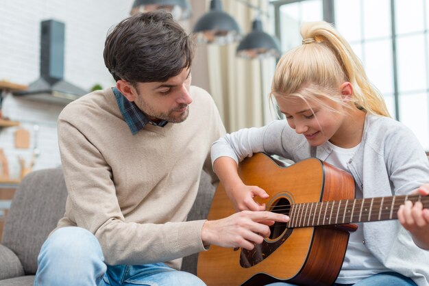 Tutor che aiuta il suo giovane studente a suonare la chitarra