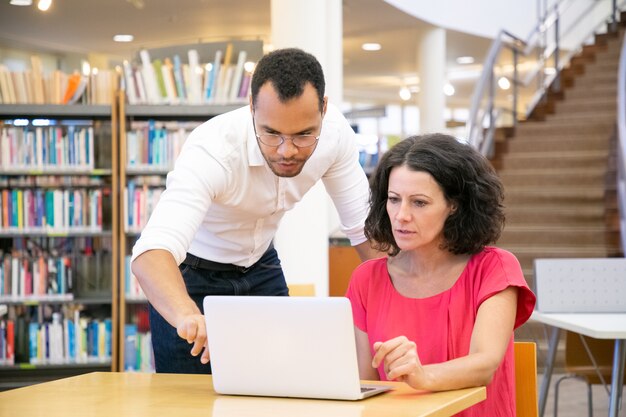 Tutor che spiega la ricerca specifica per gli studenti in biblioteca