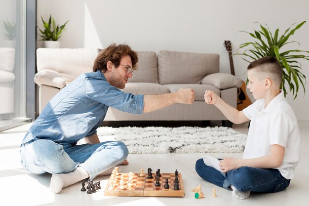 Tutor e ragazzo che giocano a scacchi sul pavimento