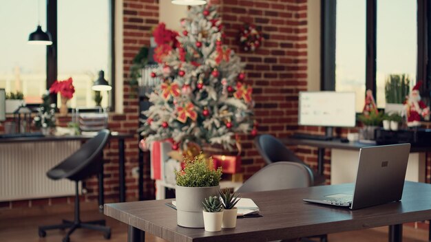 Ufficio commerciale decorato con albero di Natale e luci per celebrare le festività natalizie durante la stagione invernale. Spazio vuoto pieno di decorazioni e ornamenti natalizi, tradizione stagionale.