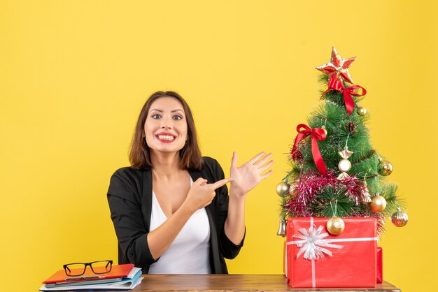 Umore di Natale con la giovane bella donna che indica la sua mano all'ufficio