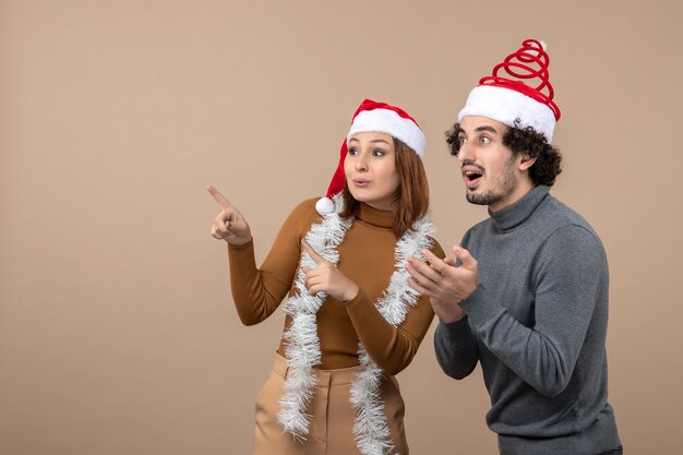 umore natalizio con coppia adorabile soddisfatta fresca eccitata che indossa cappelli rossi di Babbo Natale concentrati