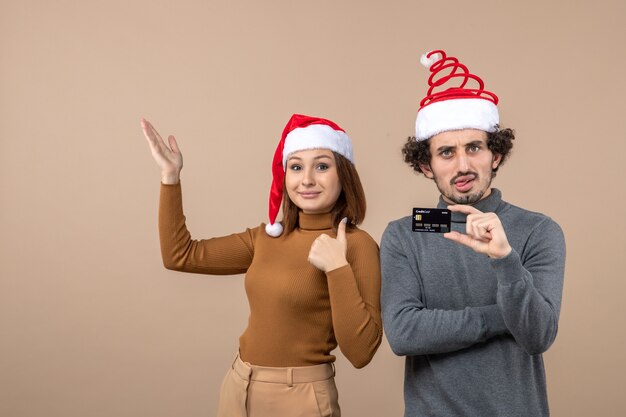 umore natalizio con coppia cool soddisfatta emotiva eccitata che indossa cappelli rossi di Babbo Natale che mostrano carta di credito