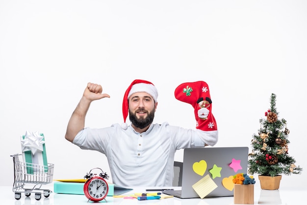 umore natalizio con giovane adulto positivo con cappello di babbo natale e indossa un calzino natalizio alla mano facendo un gesto di forza in ufficio