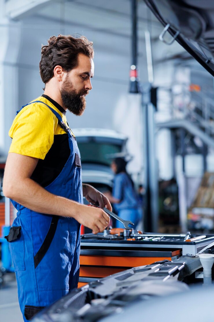 Foto gratuito un addetto al servizio auto prende una chiave inglese dalla panchina della stazione di lavoro usandola per svitare i dadi per sostituire il motore un addetto al garage di precisione usa strumenti professionali per riparare l'automobile del cliente
