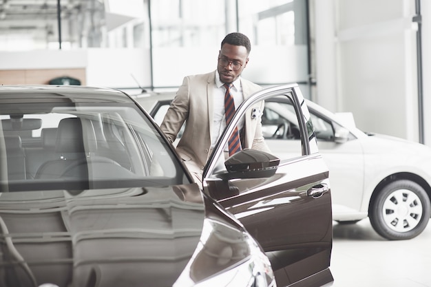 Un afroamericano ispeziona l'auto presso il concessionario di automobili. Buon affare.