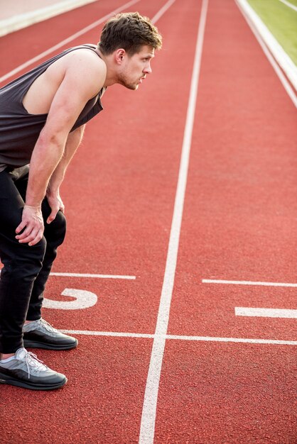 Un atleta maschio esaurito che si rilassa sulla pista di corsa