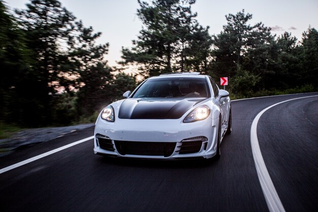 Un'automobile sportiva bianca con autotuning nero che guida sulla strada.