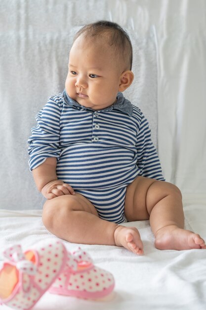 Un bambino impara a sedersi su un letto bianco