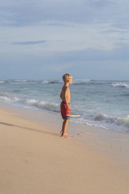 Un bambino sulla spiaggia gioca tra le onde dell'oceano. Ragazzo sull'oceano, infanzia felice. vita tropicale.