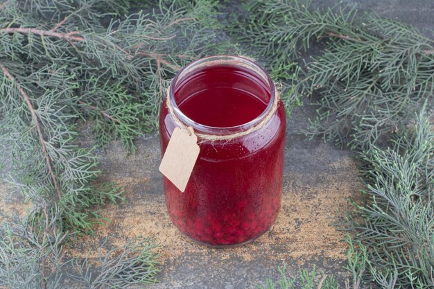 Un barattolo di succo rosso su fondo marmo. Foto di alta qualità