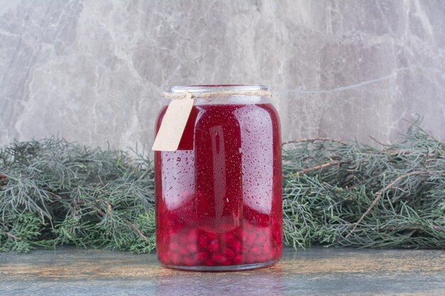 Un barattolo di succo rosso su fondo marmo. Foto di alta qualità