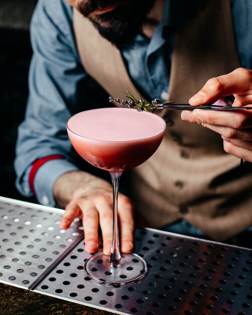 Un barista di vista frontale che prepara cocktail sul cocktail della bevanda della spremuta dello scrittorio della barra