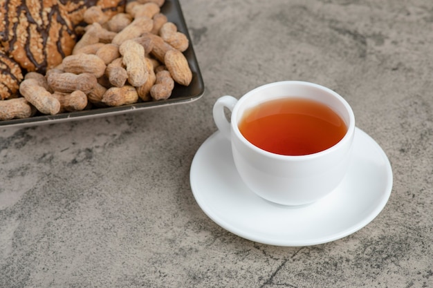 Un bel piatto di biscotti di farina d'avena con noci e una tazza di tè caldo.