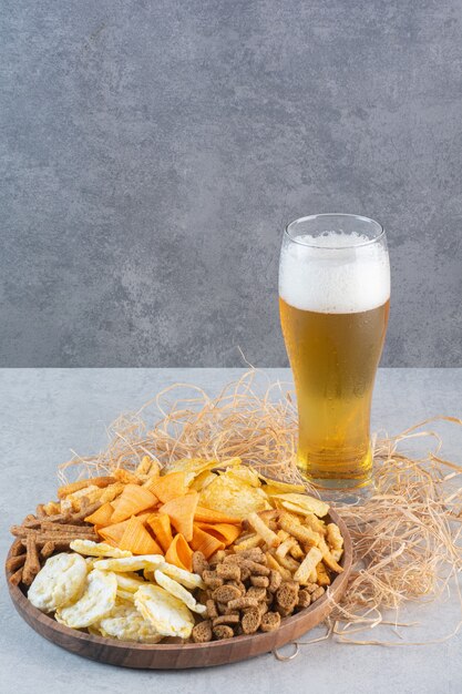 Un bicchiere di birra con frumento e patatine fritte sul fieno.