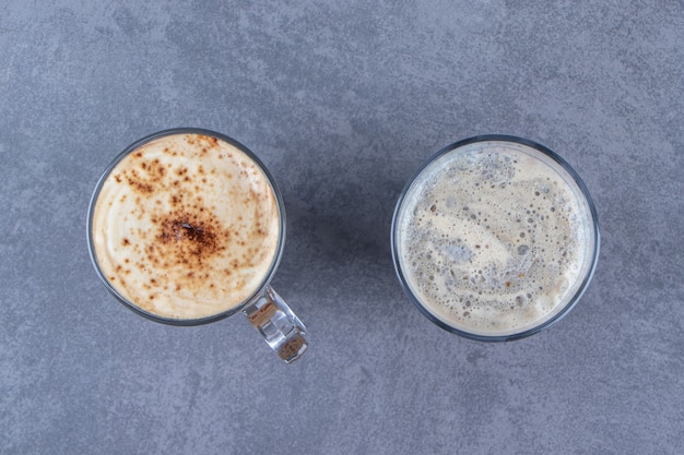 Un bicchiere di caffè blu accanto al cappuccino al cioccolato, sul tavolo blu.