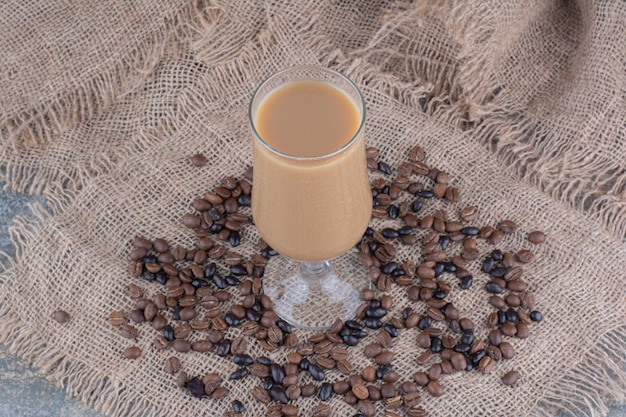 Un bicchiere di caffè con chicchi di caffè su sfondo marmo. Foto di alta qualità