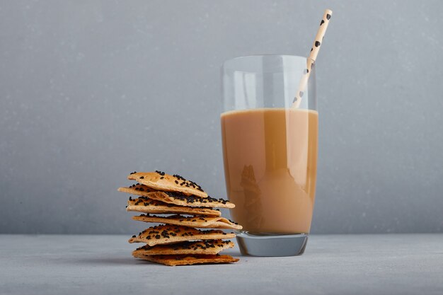 Un bicchiere di cappuccino con cracker al cumino.