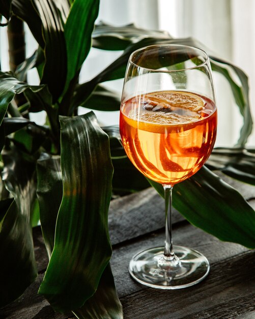 Un bicchiere di cocktail arancione davanti alla finestra