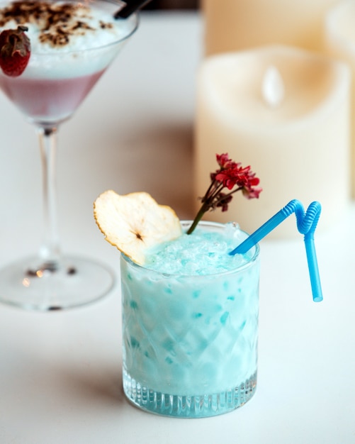 Un bicchiere di cristallo blu cocktail guarnito con una fetta di pera essiccata