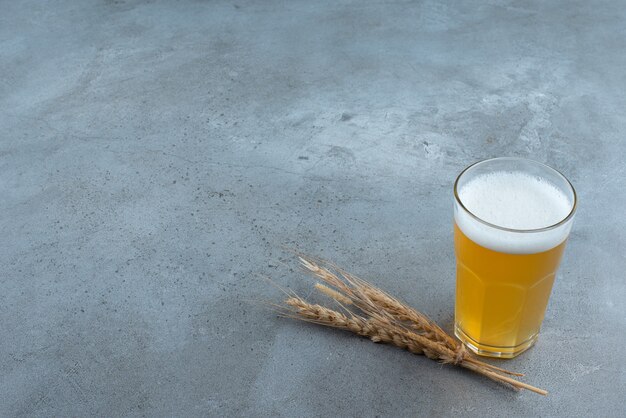 Un bicchiere di deliziosa birra e grano su sfondo grigio. Foto di alta qualità