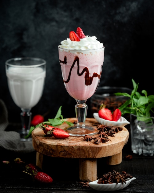 Un bicchiere di frappè alla fragola condito con panna montata e fragola