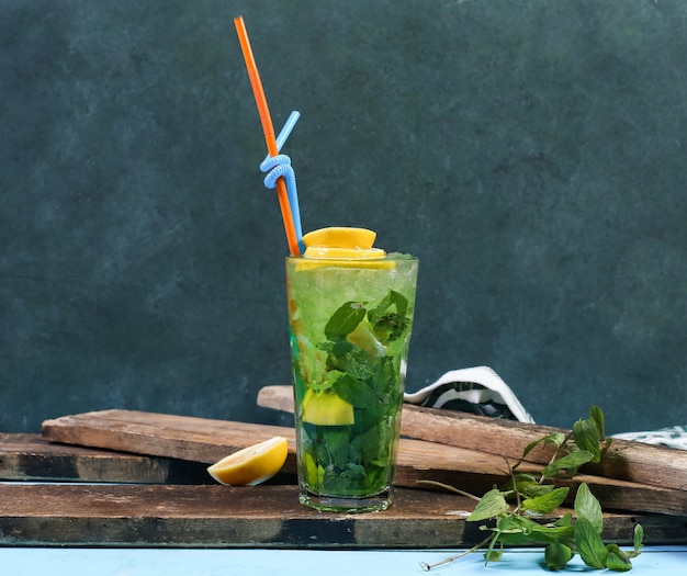 Un bicchiere di mojito verde al limone su un pezzo di legno.