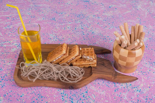 Un bicchiere di succo con cialde su un piatto di legno e in una tazza di legno