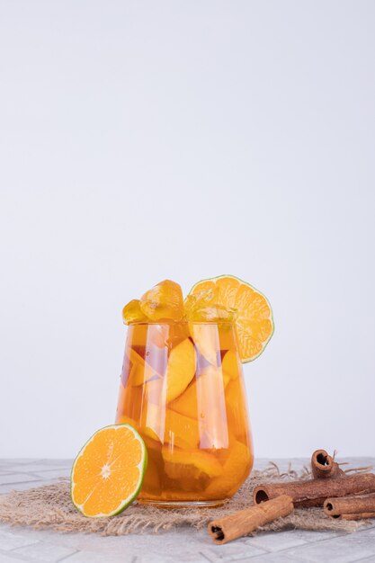 Un bicchiere di succo con fette di frutta e cannella.