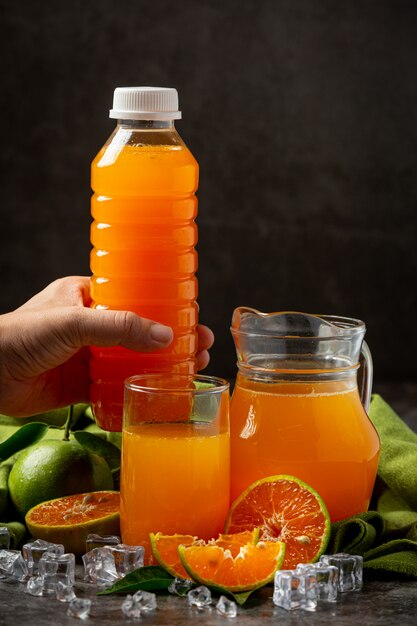 Un bicchiere di succo d'arancia e frutta fresca sul pavimento con cubetti di ghiaccio.