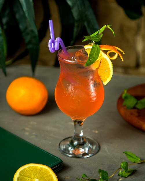 Un bicchiere di succo d'arancia guarnito con scorza d'arancia e menta