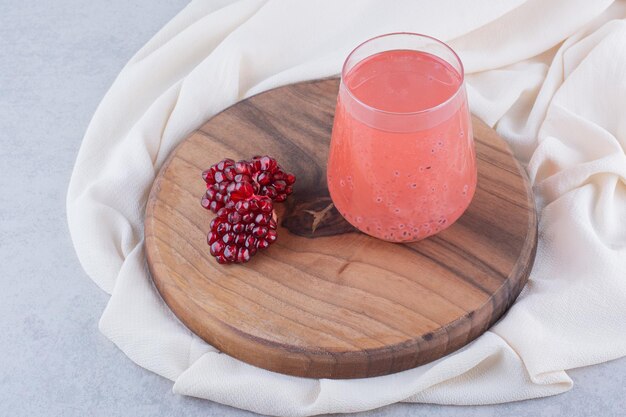 Un bicchiere di succo di melograno su tavola di legno con semi. Foto di alta qualità