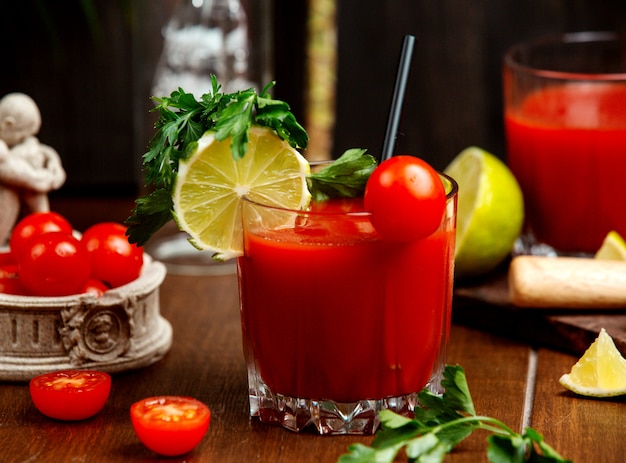 Un bicchiere di succo di pomodoro guarnito con pomodorini ciliegia e prezzemolo