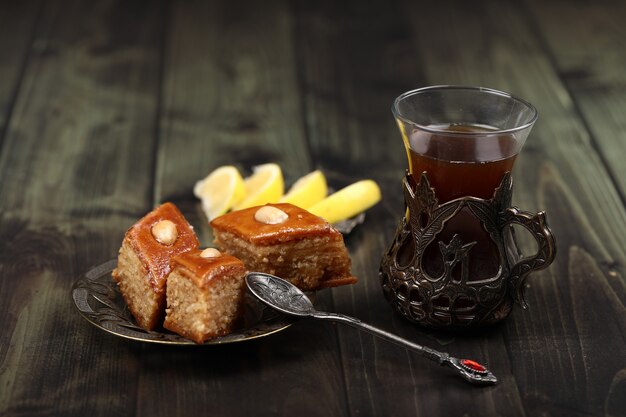 Un bicchiere di tè con pakhlava caucasica e limone su un tavolo rustico.