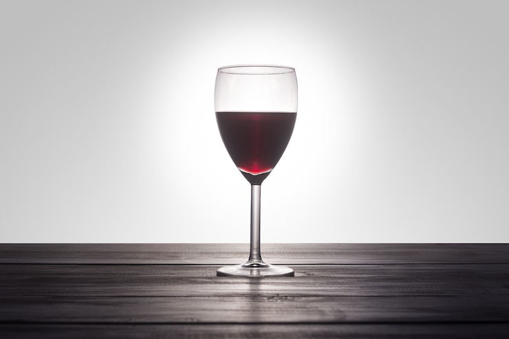Foto gratuito un bicchiere di vino rosso su una superficie di legno