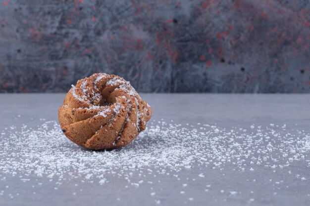 Un biscotto e una polvere di vaniglia sparsi sulla superficie del marmo