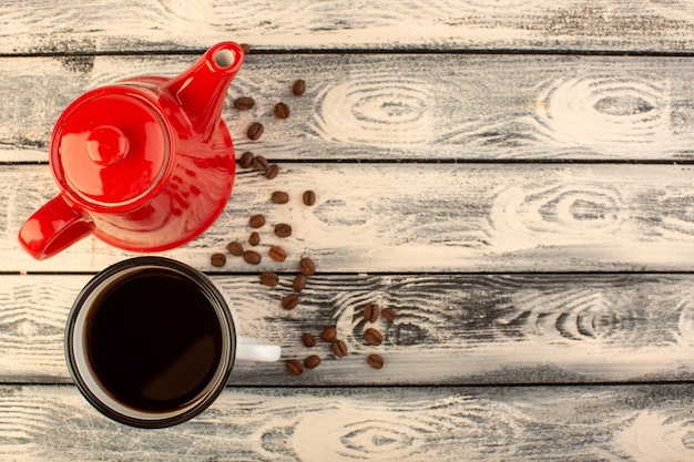 Un bollitore rosso con vista dall'alto con una tazza di caffè e semi di caffè marroni sullo scrittorio rustico grigio beve il colore del caffè