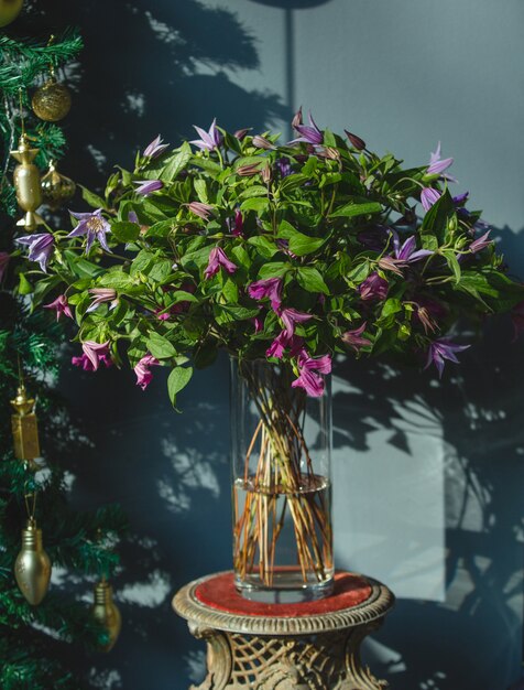 Un bouquet di fiori viola con foglie verdi all'interno di un vaso