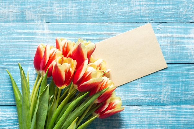 Un bouquet di tulipani e un pezzo di carta per il testo su uno sfondo di legno